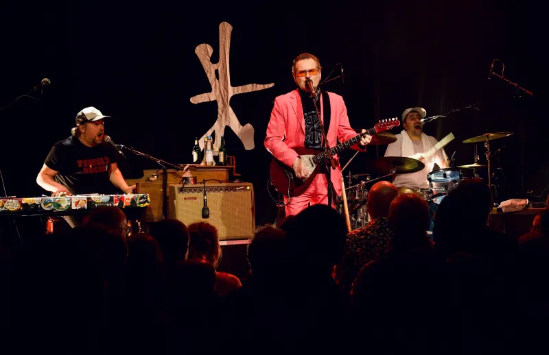 Konzert: Sänger im pinken Anzug mit Gitarre, Leo Lazar am Schlagzeug